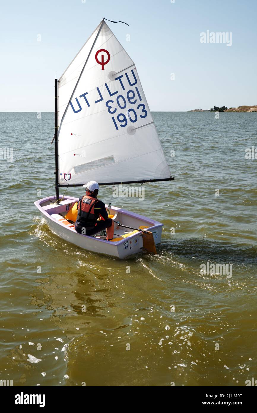 Nida, Lithuania - 24 July 2021: Young child sailing the Optimist, a small, single-handed sailing dinghy intended for use by children and teenagers up Stock Photo