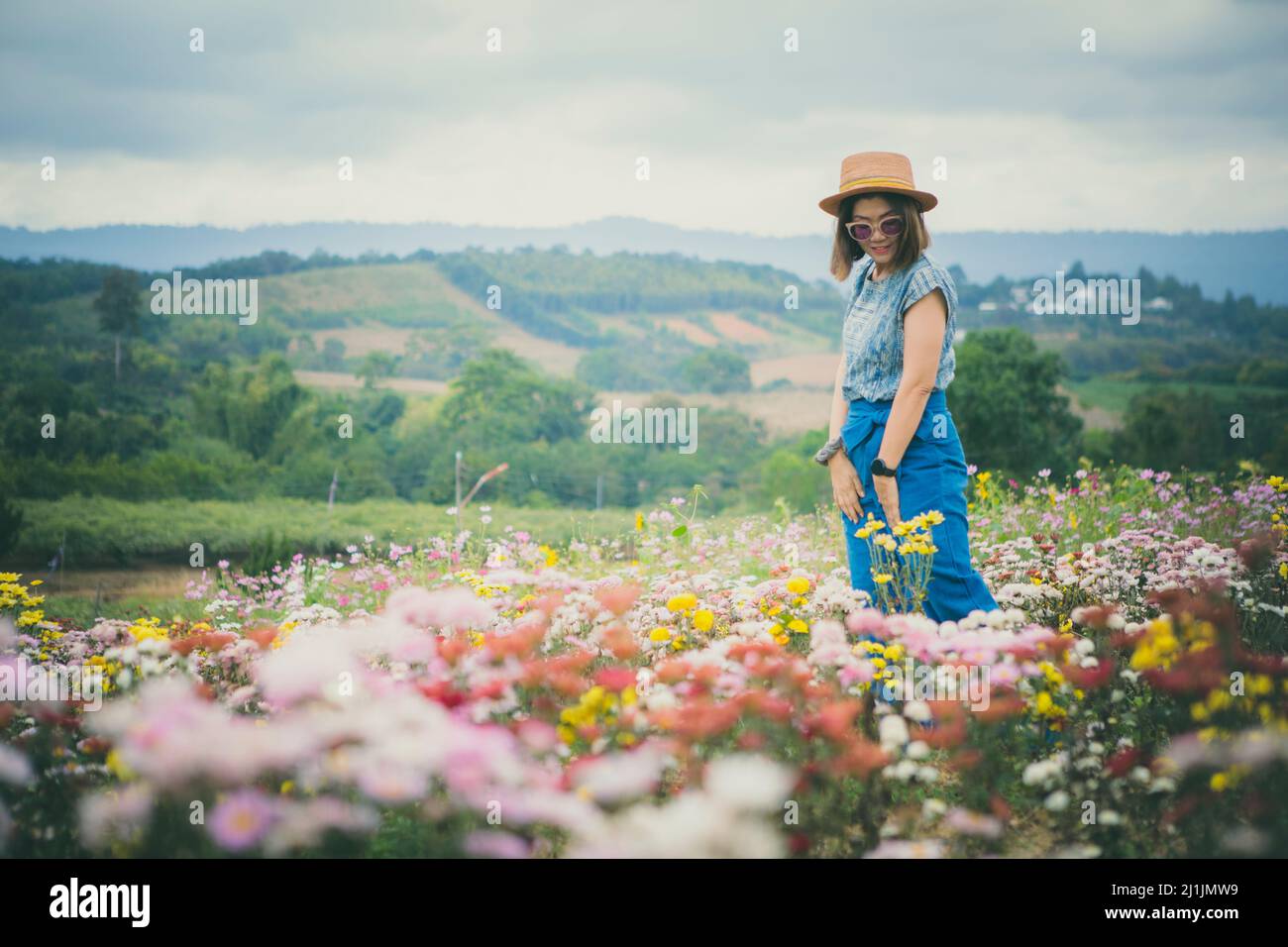 woman standing in blooming flower garden with relaxing mood Stock Photo