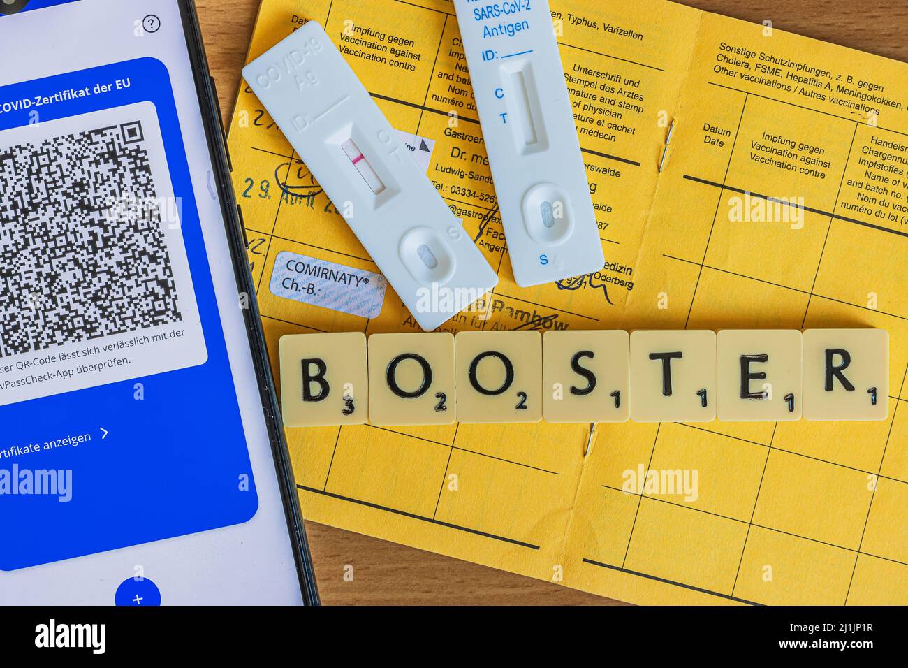 Opened yellow vaccination card from the World Health Organization with triple vaccination against corona virus. Smartphone with electronic vaccination Stock Photo