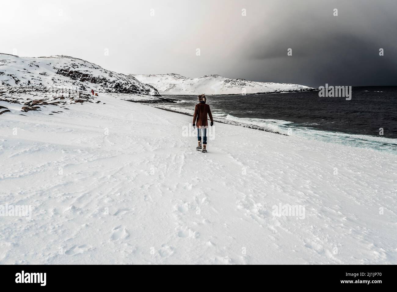Man walking on the snow near the sea in mountain area Stock Photo