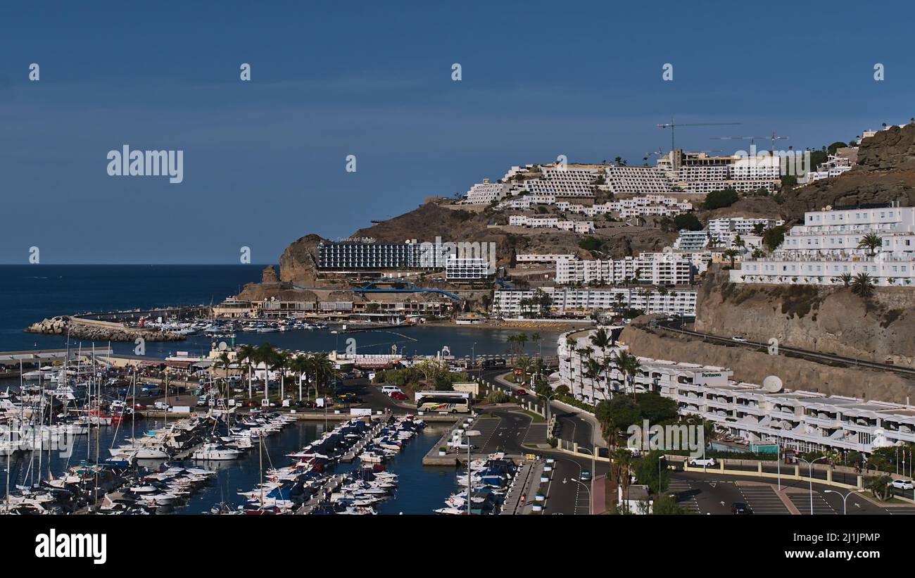 Cityscape of holiday resort Puerto Rico in the south of Gran Canaria island, Spain with large hotel complexes on the hills, marina and beach. Stock Photo