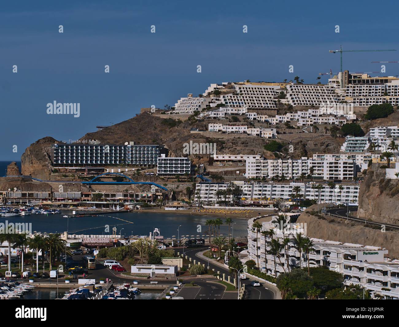 View of resort town Puerto Rico, southern Gran Canaria, Spain with large hotel buildings on the hills and beach on sunny day in winter season. Stock Photo