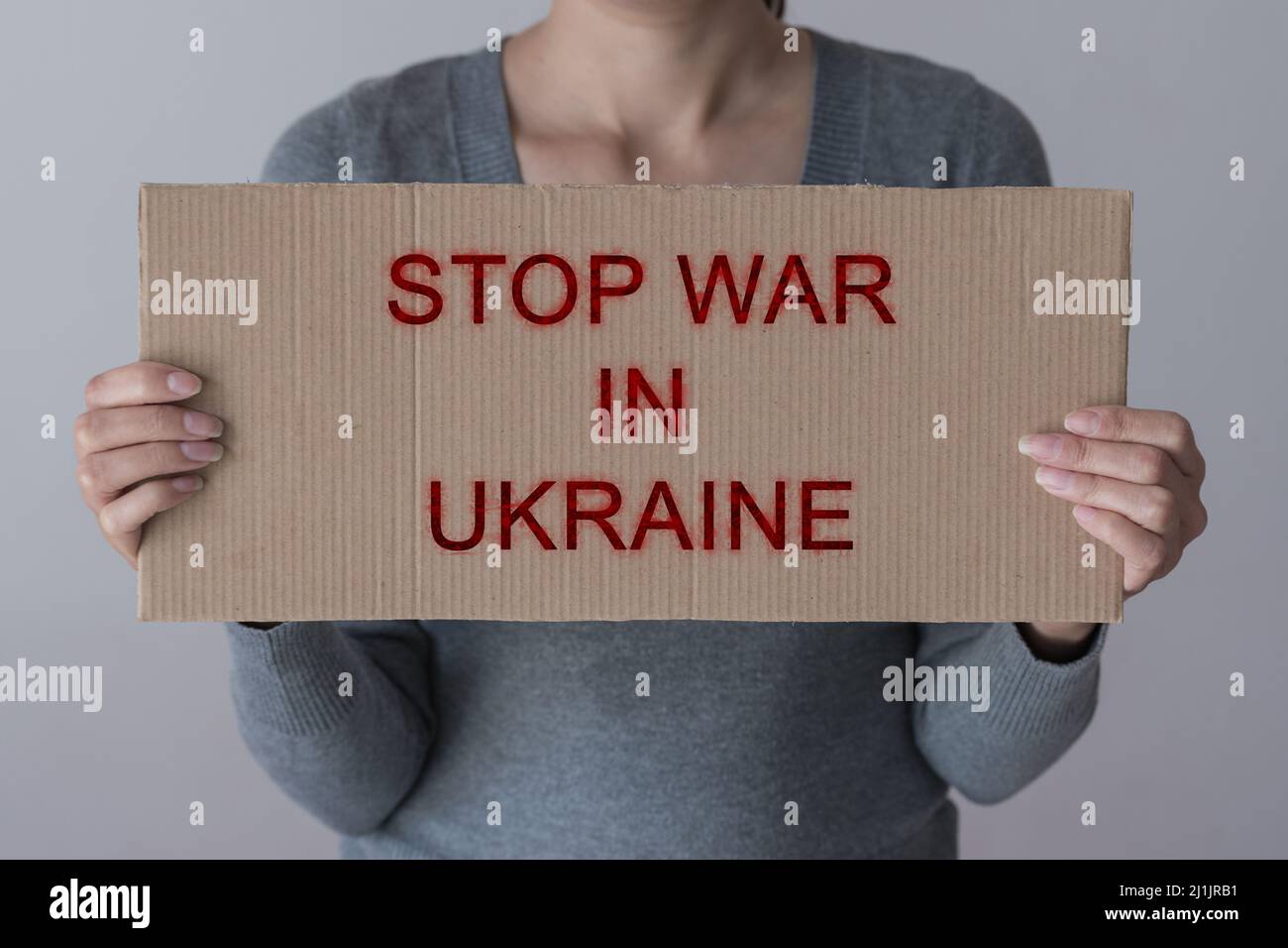 A woman holds paper placard with sign 'STOP WAR IN UKRAINE' Stock Photo
