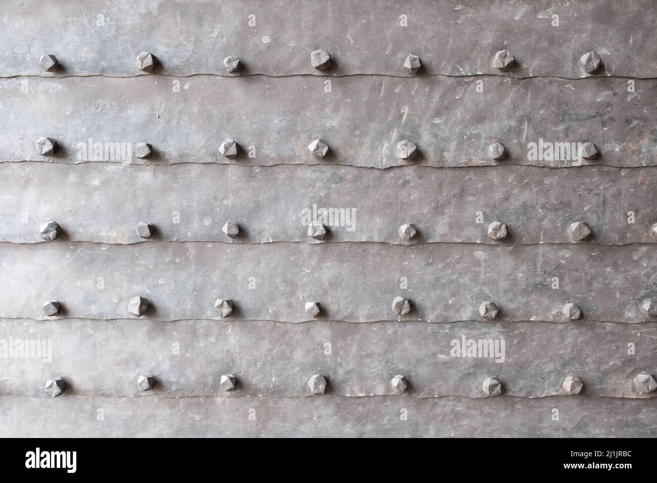 Background of metal surface from sheets with rivets, close-up. Texture of the iron gate. A metal relief backing for branding, calendar, postcard Stock Photo
