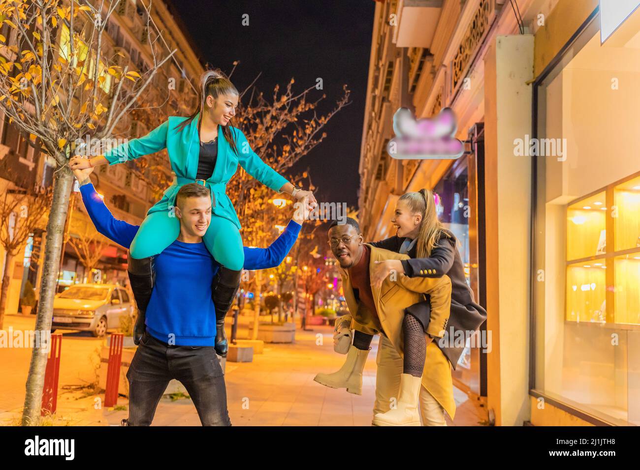 Two multiracial couples are doing a piggyback ride together and having ...
