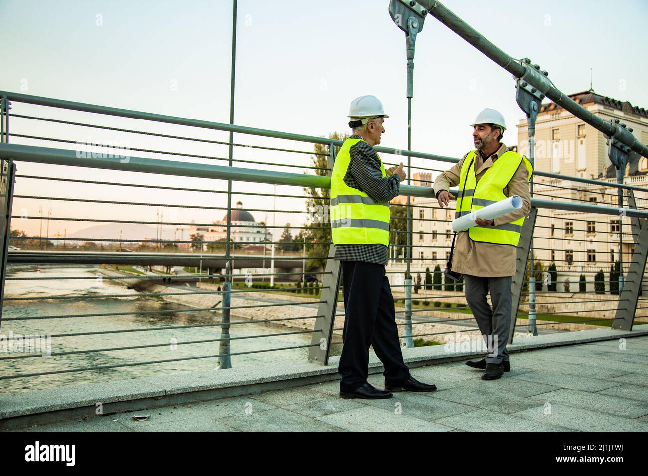 Two senior construction managers are standing on the bridge while talking and smiling Stock Photo