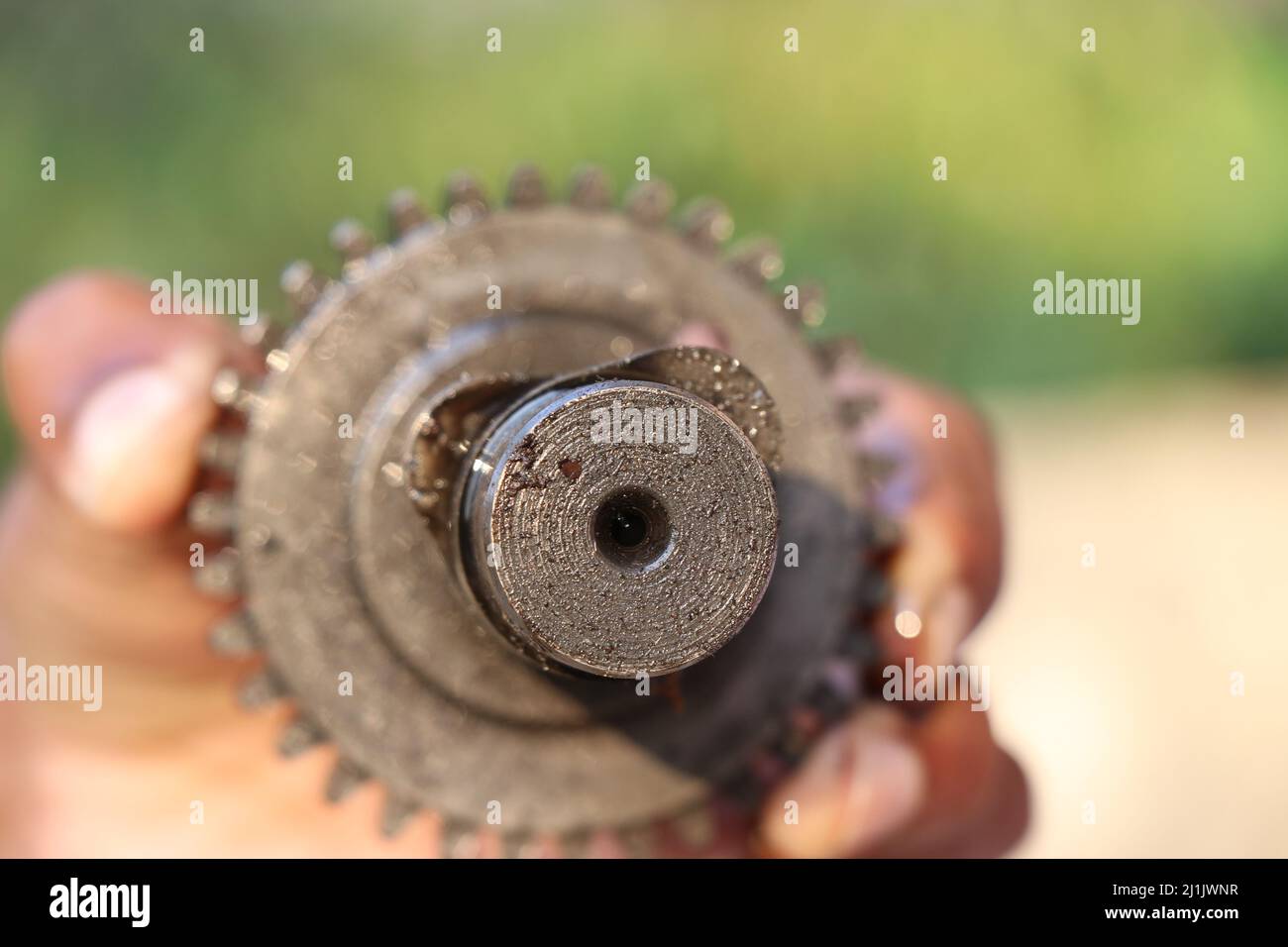 Focus on Tip of the Camshaft sprocket part of an internal combustion engine held in hand, Repairing an engine concept Stock Photo