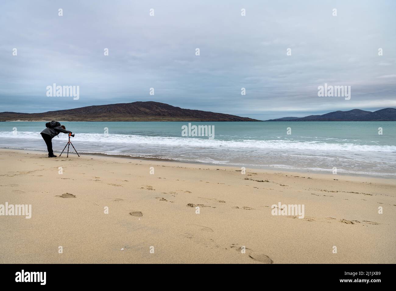 Photographer (unidentifiable) taking a long exposure image of the sea on Luskentyre Beach, isle of Harris, Scotland Stock Photo