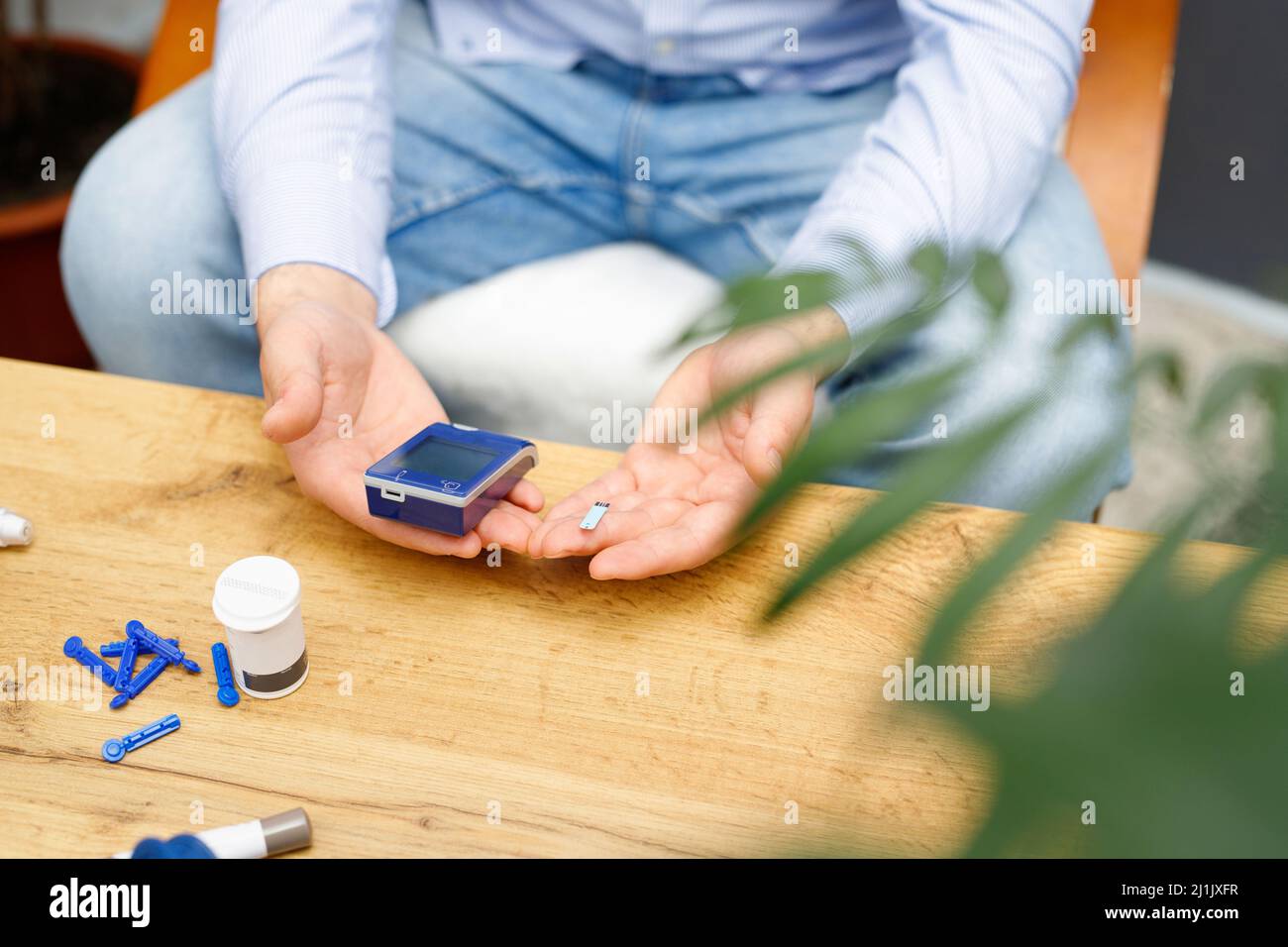 Man Using Glucometer Man using glucometer and stripe for checking blood sugar level at home ...