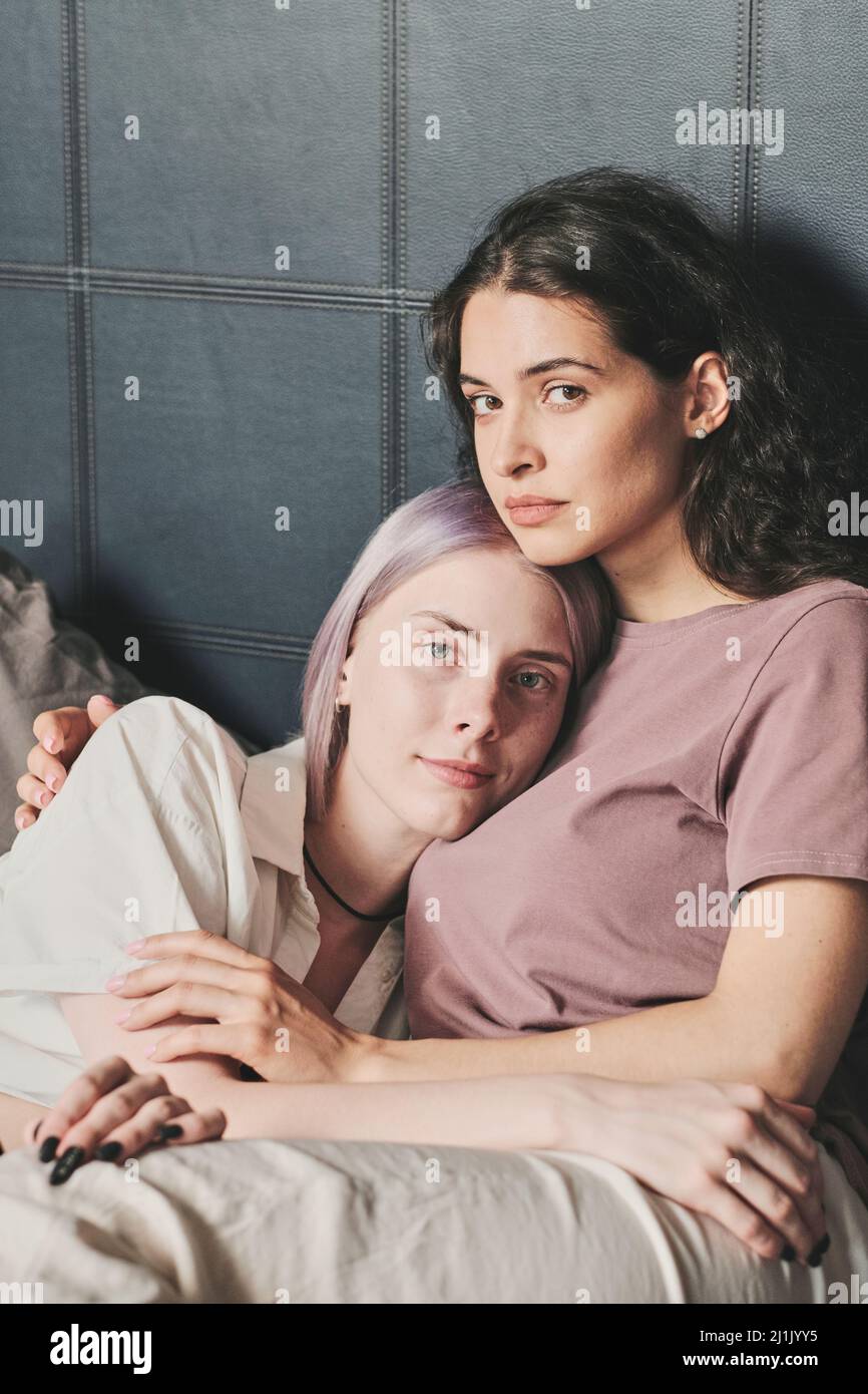 Portrait Of Content Attractive Young Lesbians In Pijamas Hugging In Bed