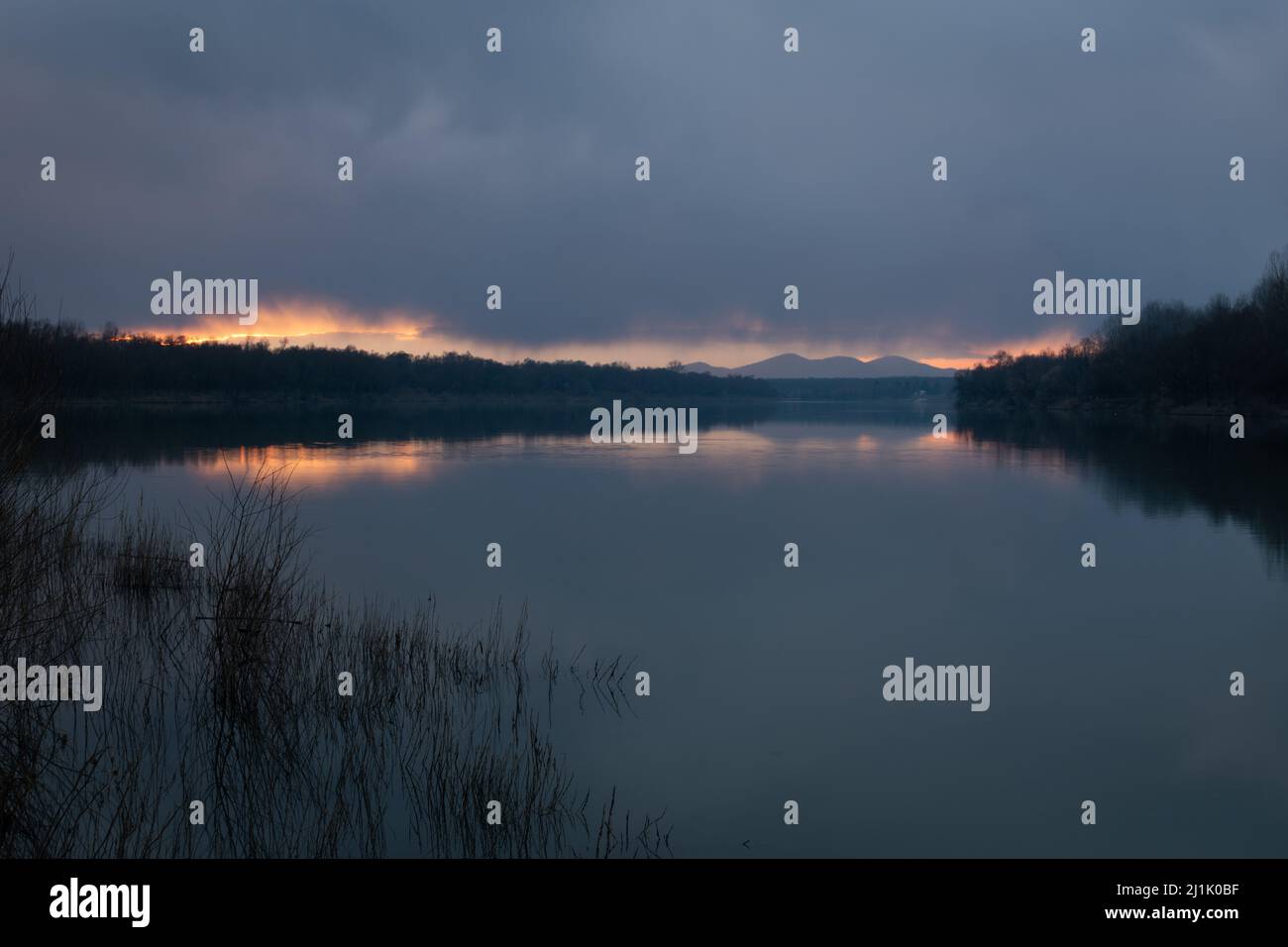 Landscape of River Sava and Motajica mountain with dark clouds at dusk Stock Photo