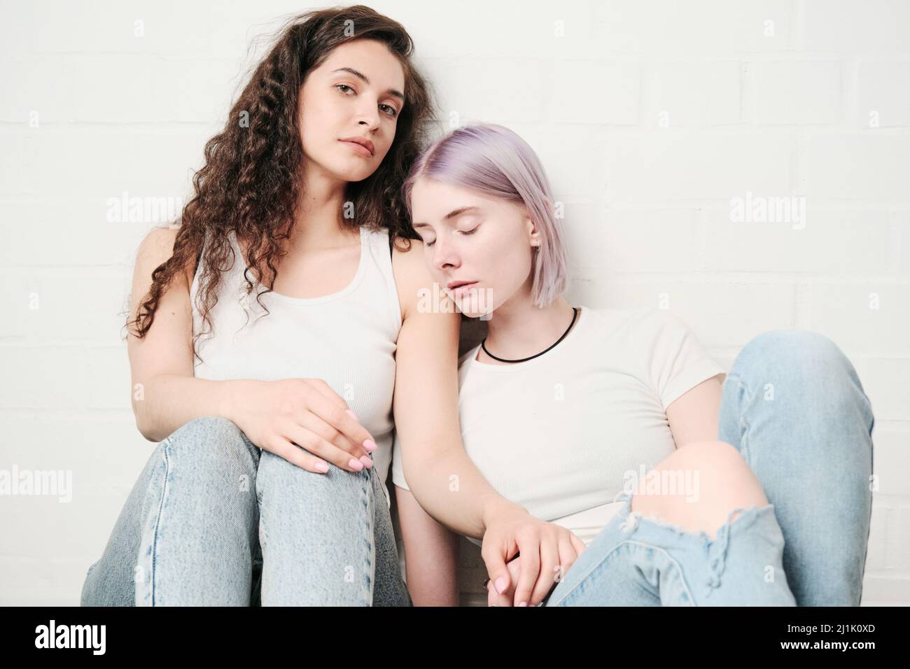 Portrait of attractive young woman sitting on floor while her