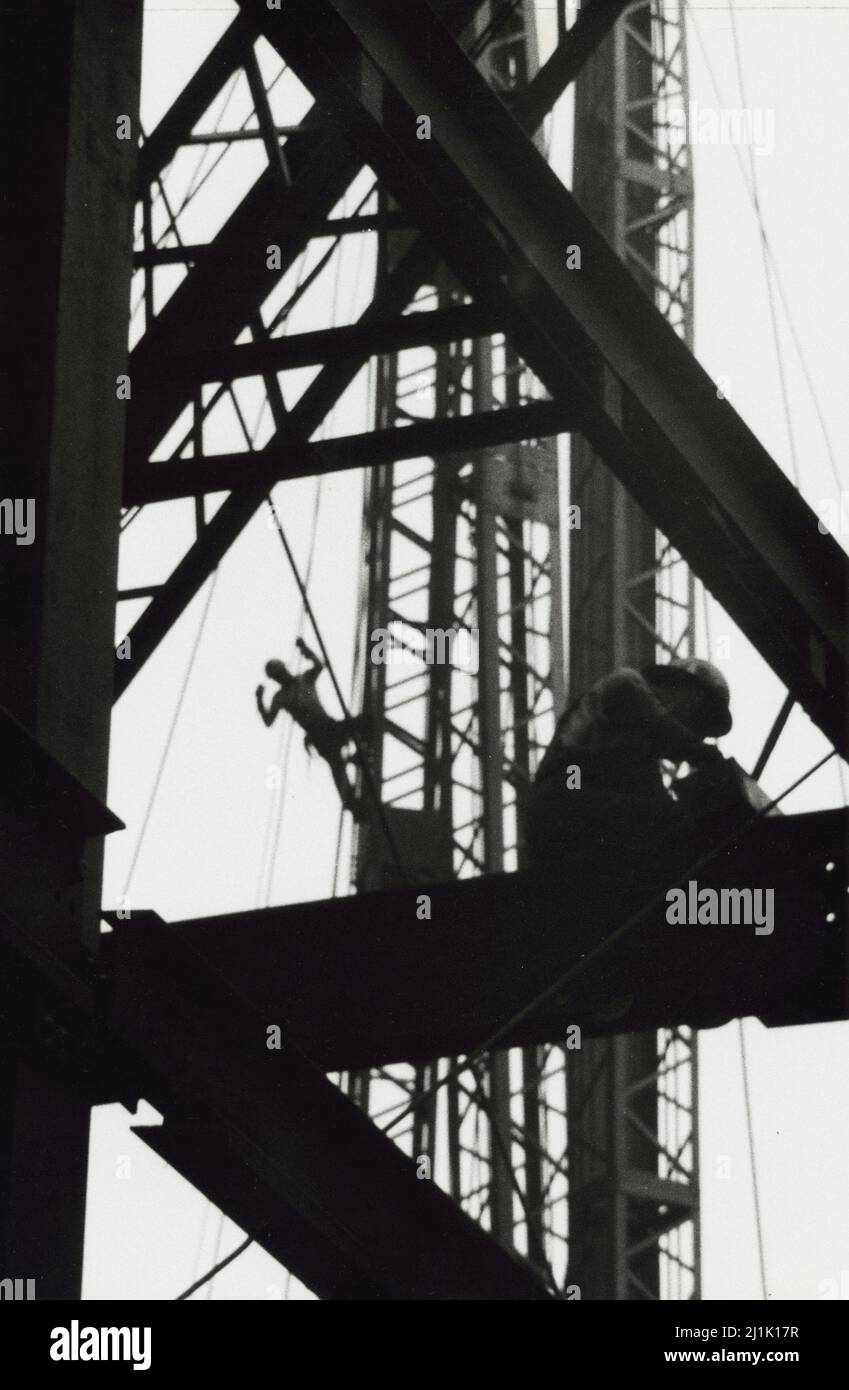 Construction worker leaning off of a crane. Photo by Angelo Rizzuto. 1957. Stock Photo