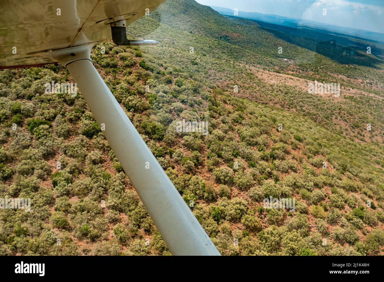 View of the arid landscape of the Great Rift Valley during the dry season from the window of a small sports plane flying over the Kenyan savannah Stock Photo