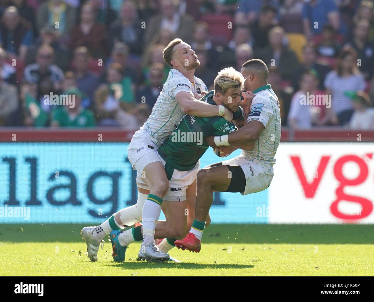 London Irish's Will Goodrick-Clarke (centre) is tackled by Northampton Saints' Rory Hutchinson (left) and Courtnall Skosan (right) during the Gallagher Premiership match at the Brentford Community Stadium, London. Picture date: Saturday March 26, 2022. Stock Photo