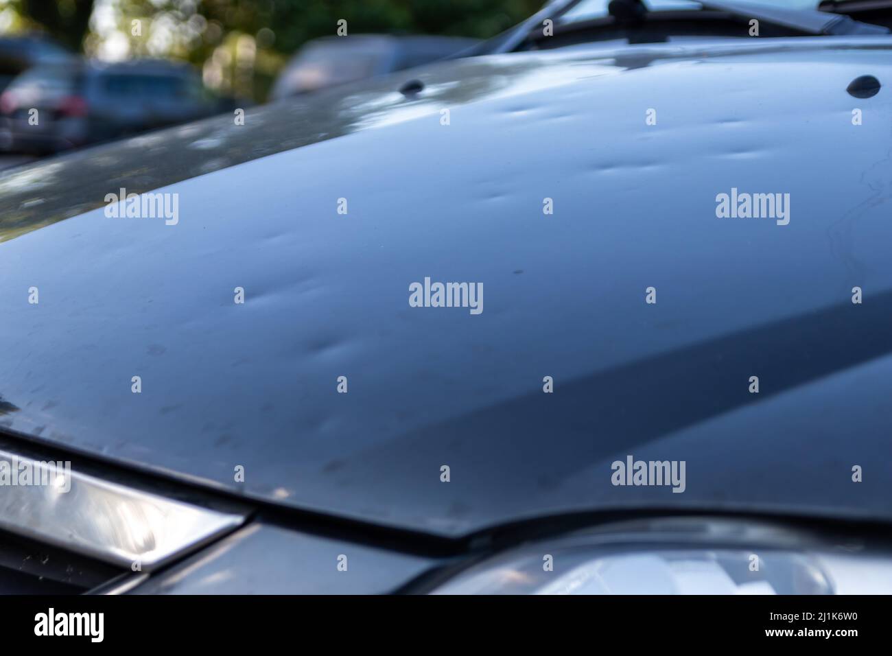 Car engine hood with many hail damage dents show the forces of nature
