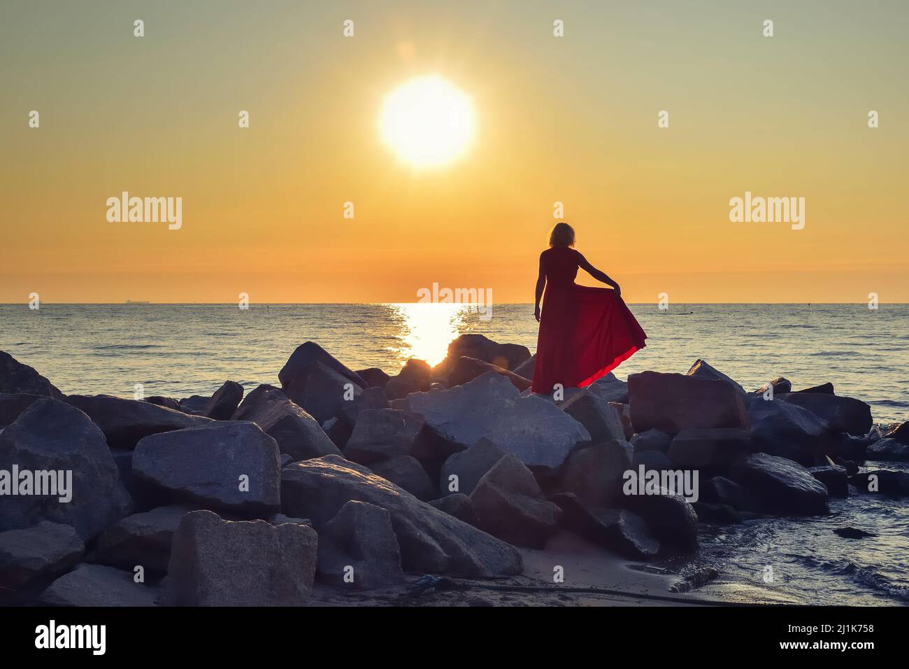 Beautiful seaside landscape with a woman on the beach. Girl in a red ...
