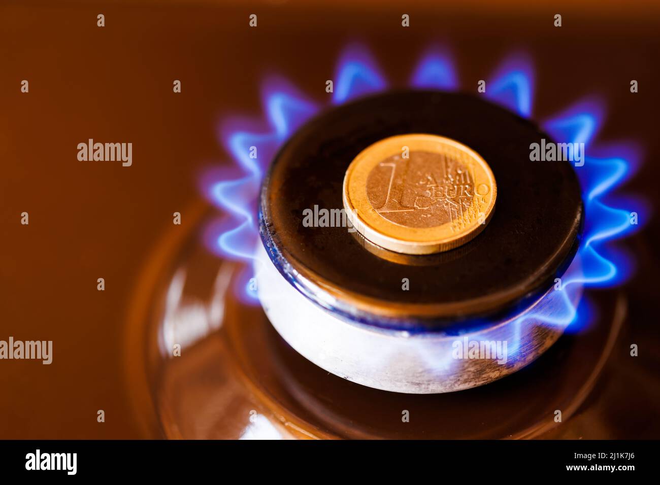 gas stove burner with one euro coin laid on top, burning natural gas with blue flame Stock Photo