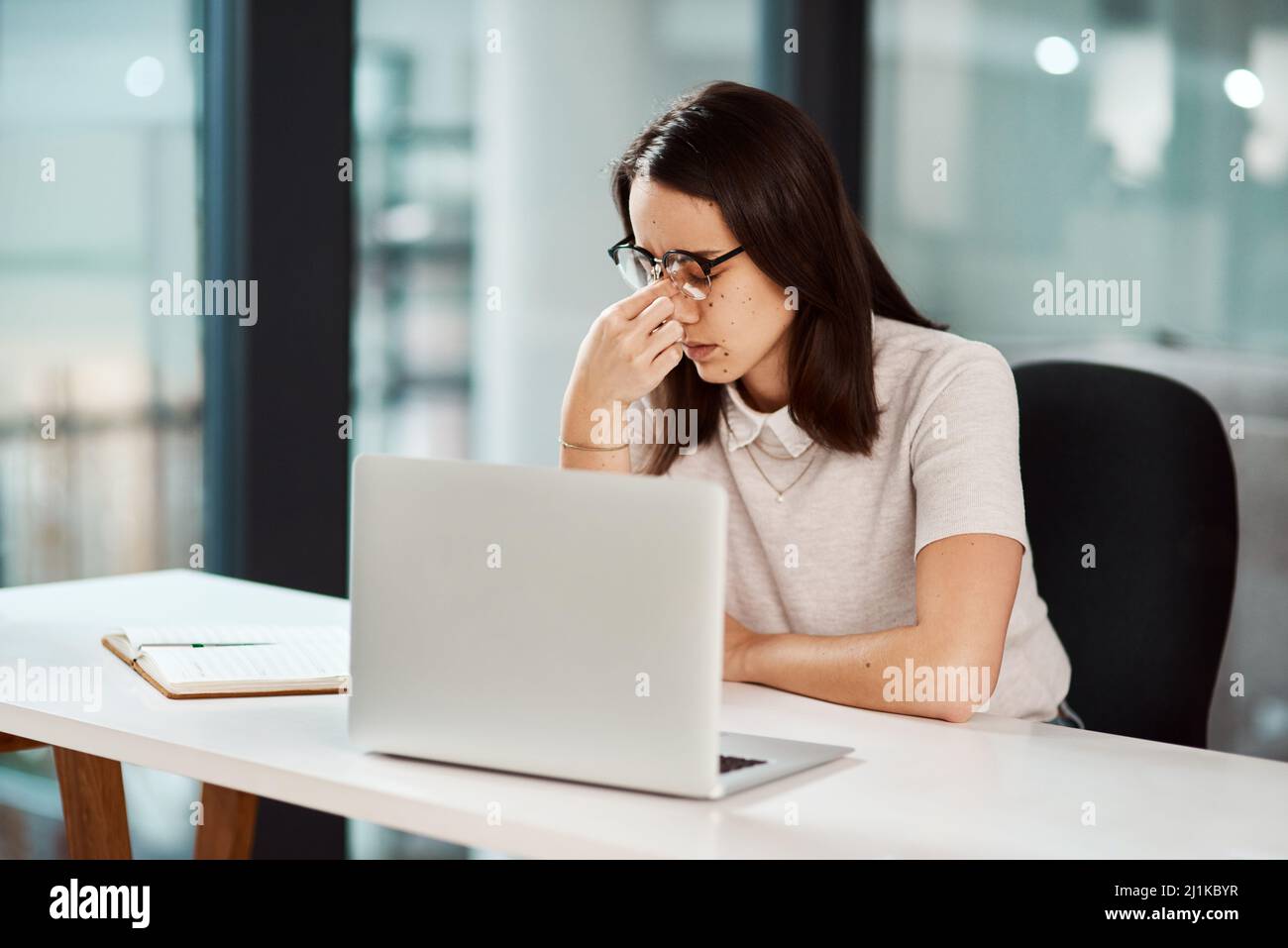 Ill need to work overtime to overcome these deadlines. Shot of a young businesswoman looking stressed out while working in an office. Stock Photo