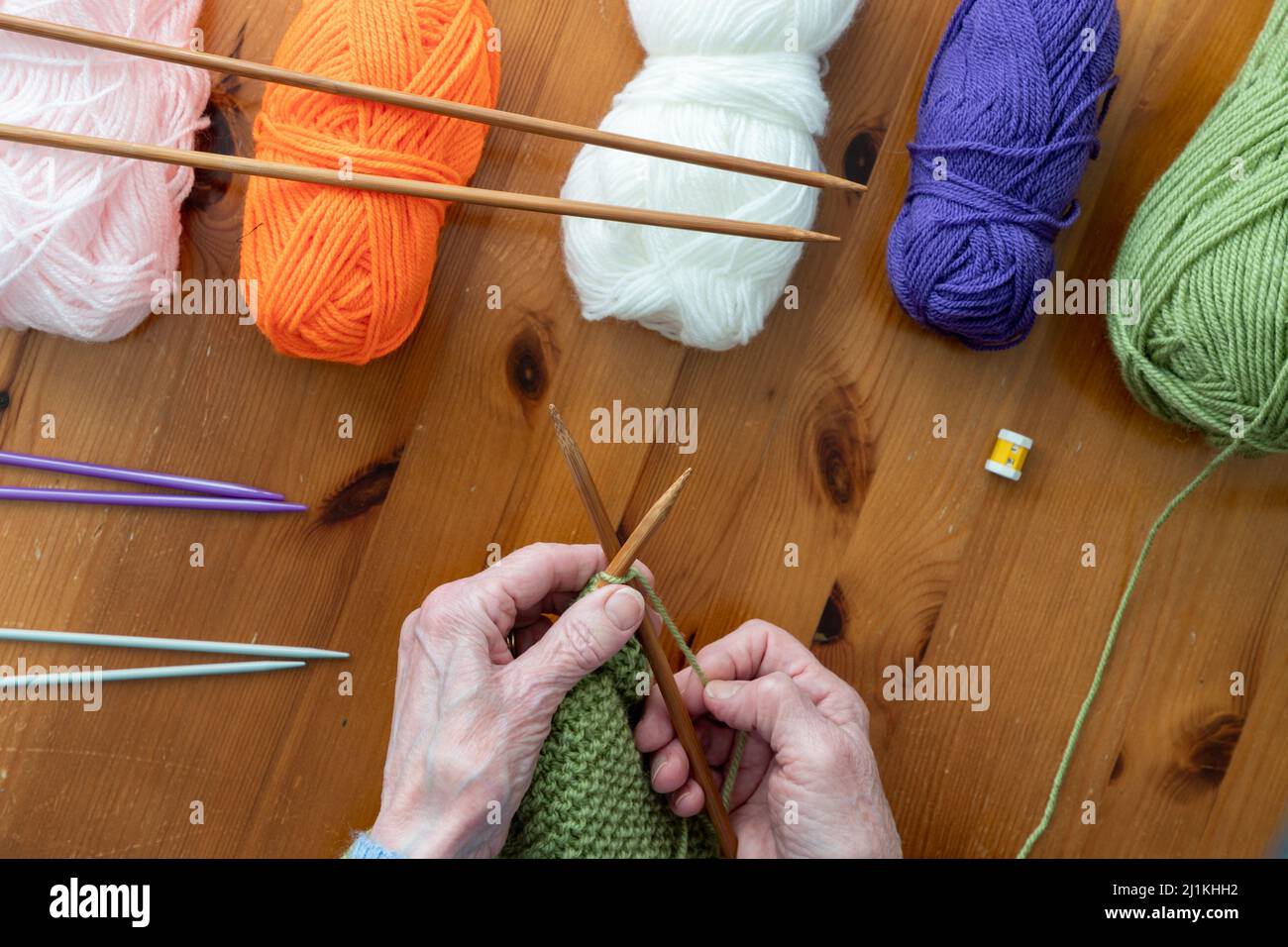 Hands of older person with arthritis enjoying knitting in a flat lay