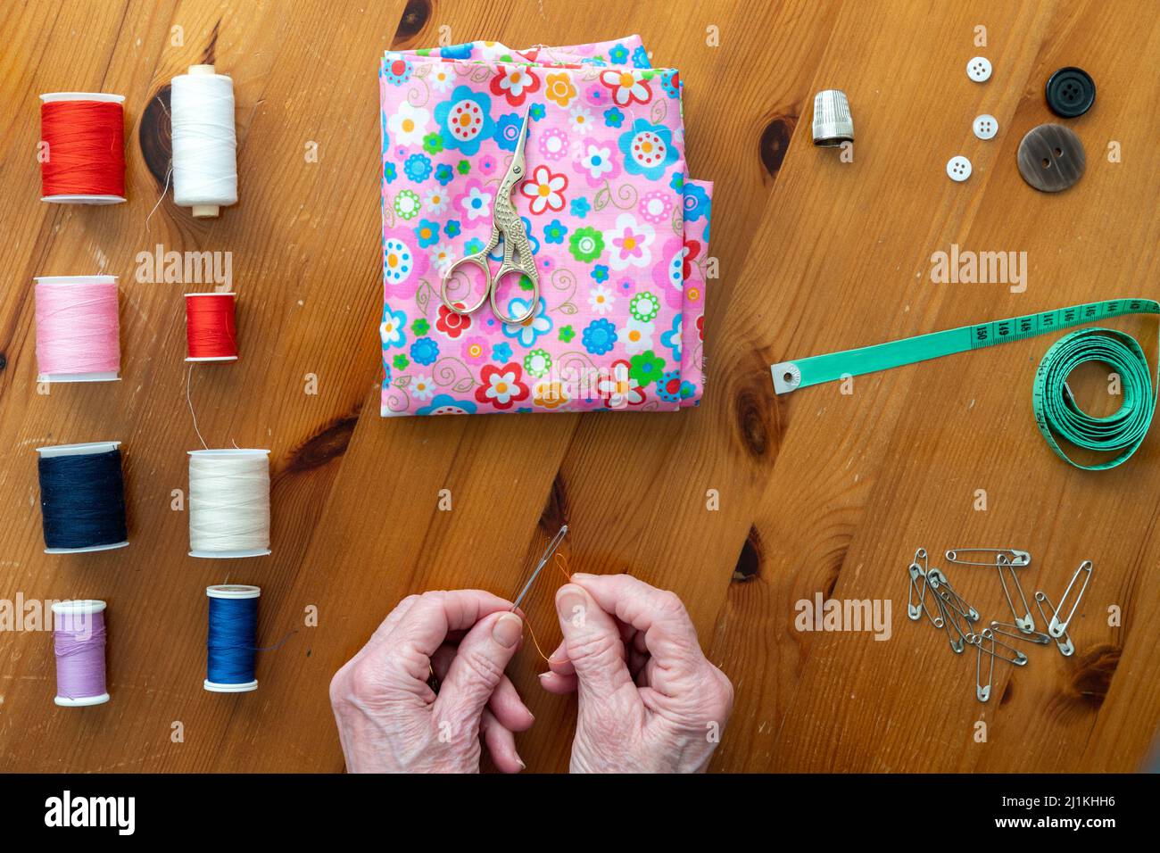Hands of older person with arthritis enjoying sewing in a flat lay style surrrrounded by sewing accessories Stock Photo