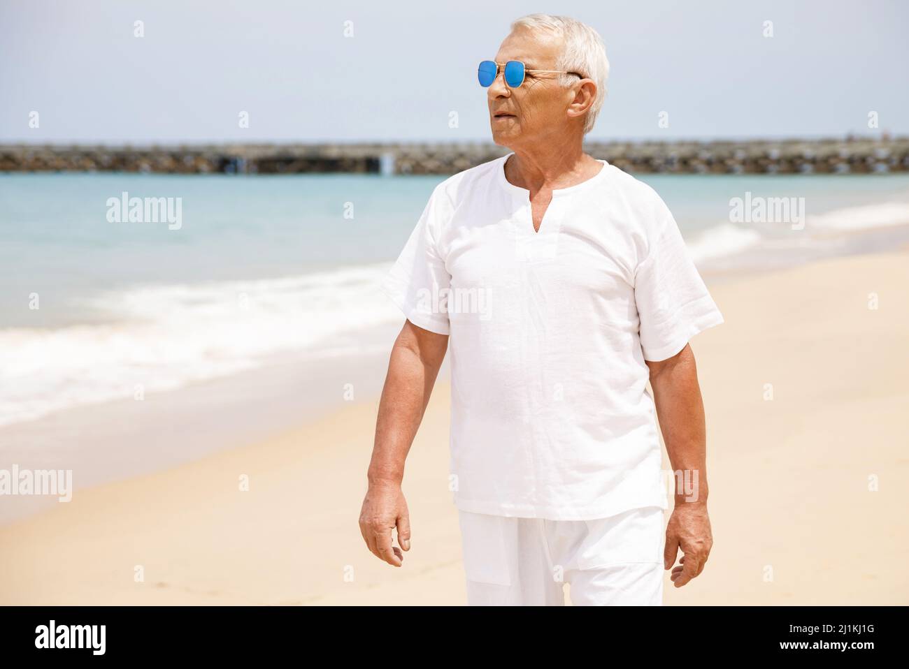 Happy senior man walking on the beach Stock Photo