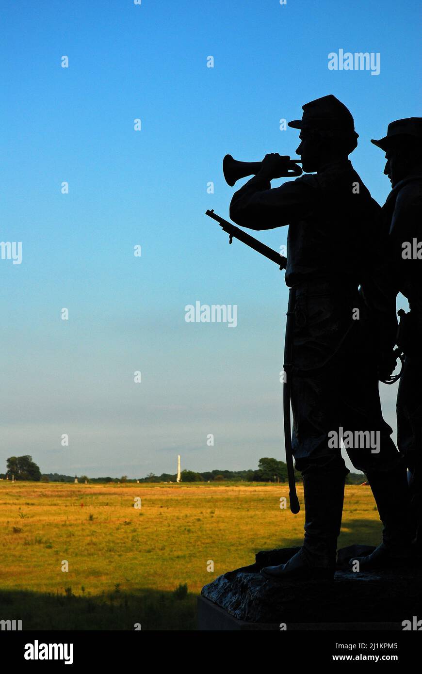 A sculpture of a bugler and soldier of the Virginia Memorial are silhouetted in Gettysburg National Battlefield Stock Photo
