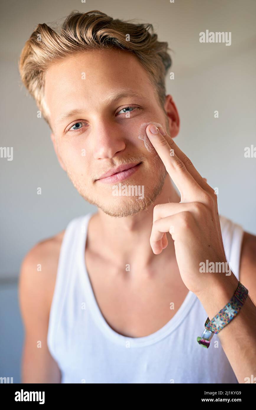 Keep your skin looking hydrated. Cropped shot of a young man applying moisturizer to his face. Stock Photo