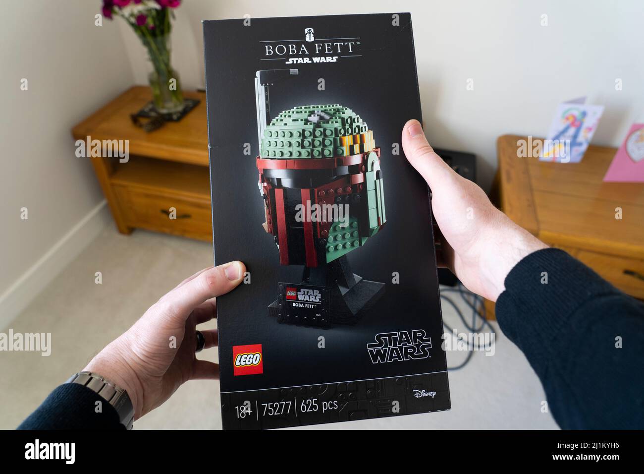 A man in his forties holding a box of 18+ lego for the scale model head of the bounty hunter Boba Fett from Star Wars. UK. Theme: adult hobbies Stock Photo