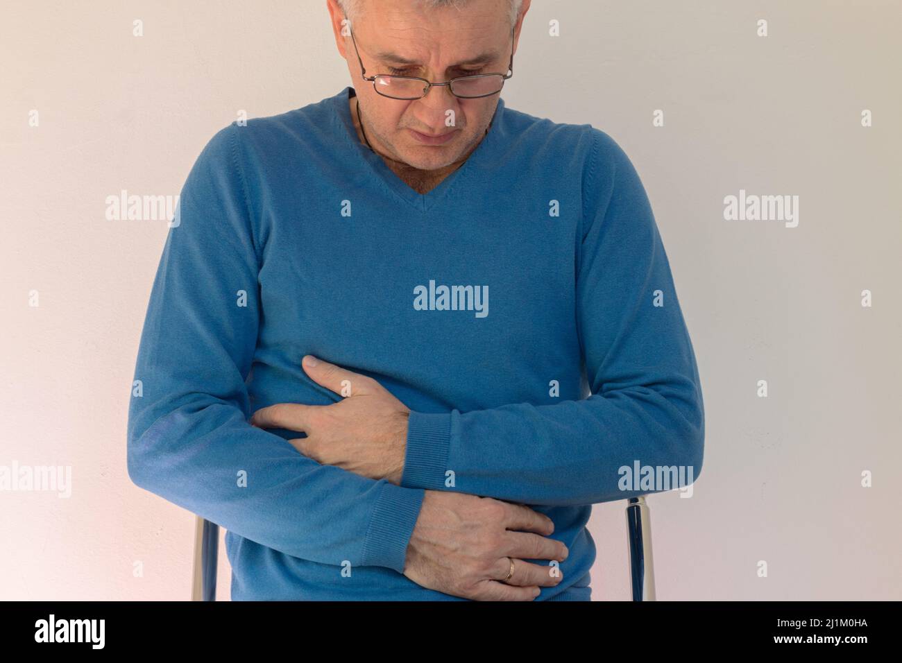 Mature man having painful stomach ache, chronic gastritis or abdomen bloating Stock Photo