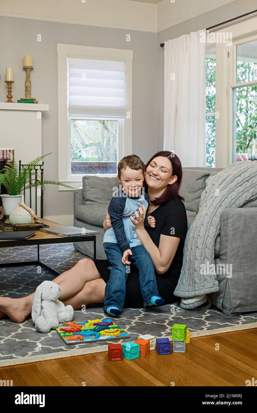 A Beautiful Pregnant Mom Trying to Work From Home with a Toddler Stock Photo