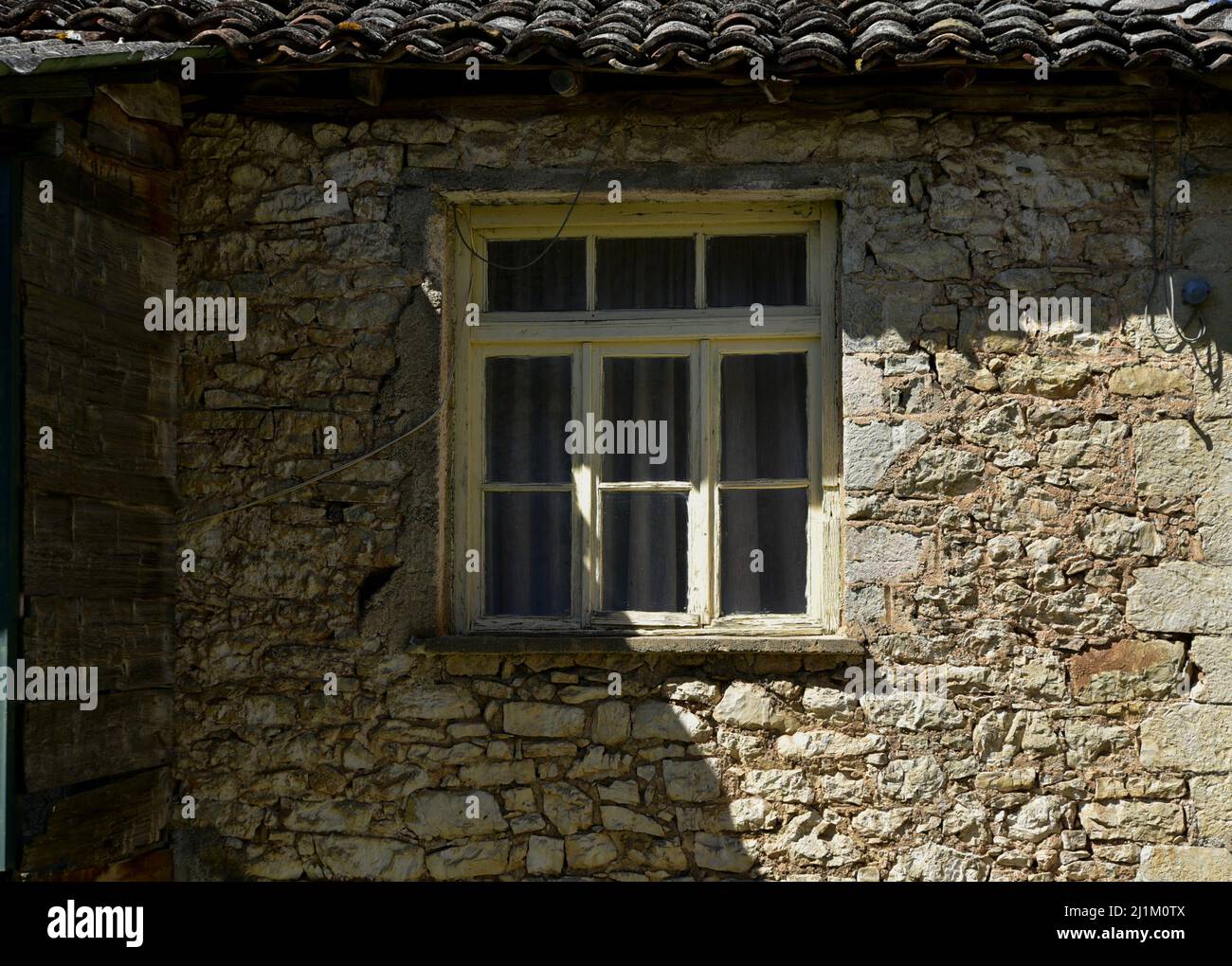 Old rural house facade with a clay tile rooftop and an antique wooden ...
