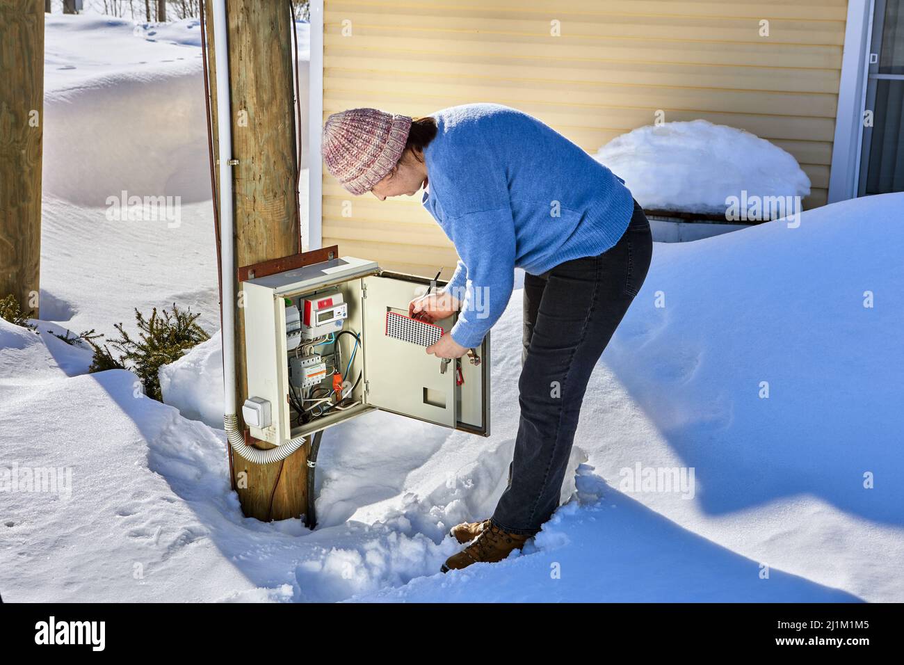 An outdoor switchboard with an electric meter, woman taking readings. Stock Photo