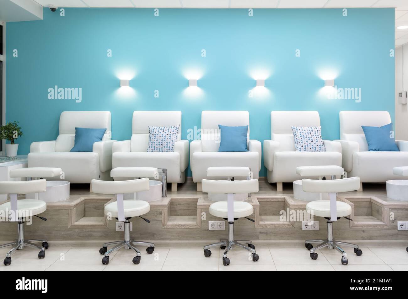 Nail salon interior, front view of modern pedicure armchairs in manicure shop or spa room. Inside bright beauty studio with blue and white design. Cle Stock Photo