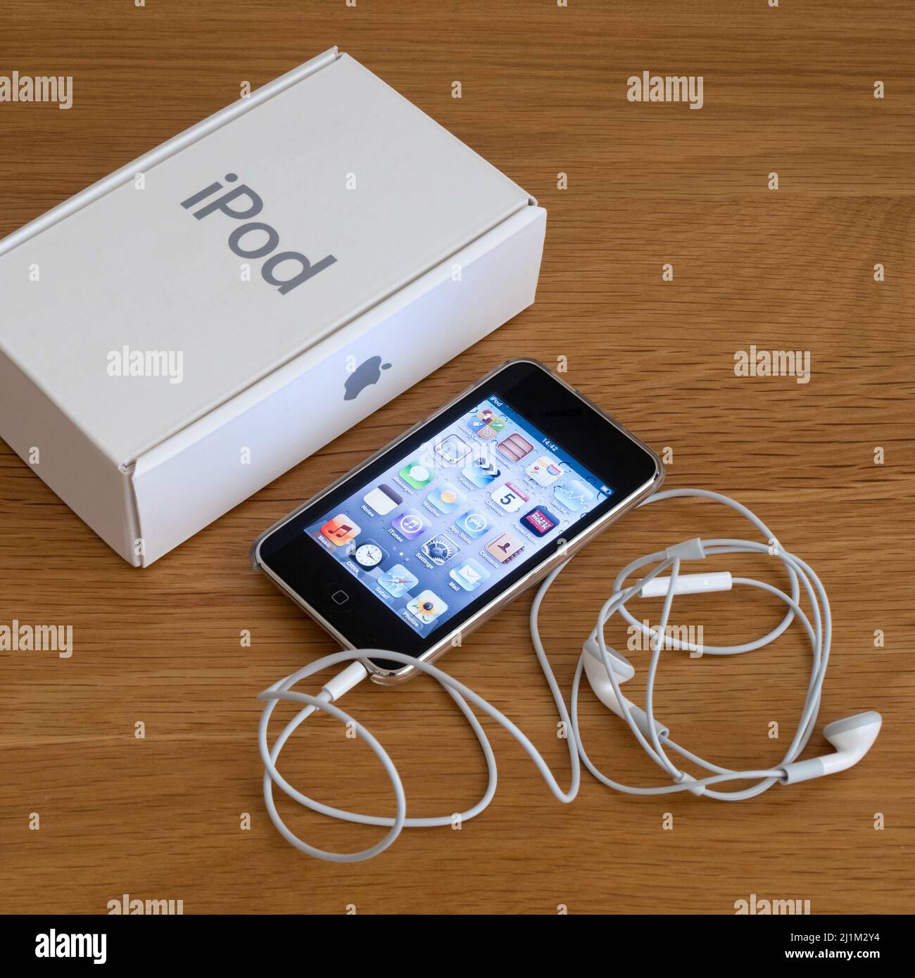 STOCK PHOTOGRAPH - Apple iPod touch (3rd generation) portable MP3 music player on wooden desk surface with box and headphones Stock Photo