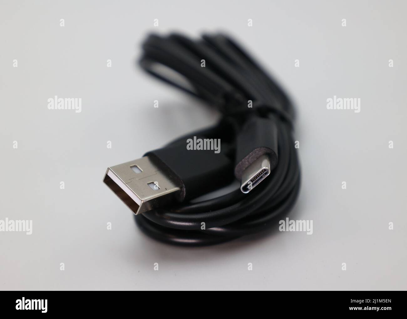 A cable wrapped up in front of a white background. The cable is USB C but is lower speed. Stock Photo