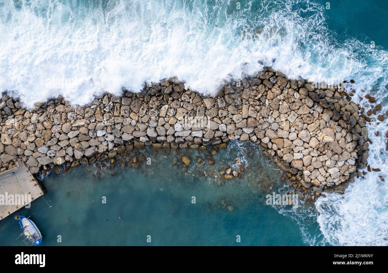 Aerial drone of stormy windy waves hitting with power the breakwater. Extreme weather at sea. Stock Photo