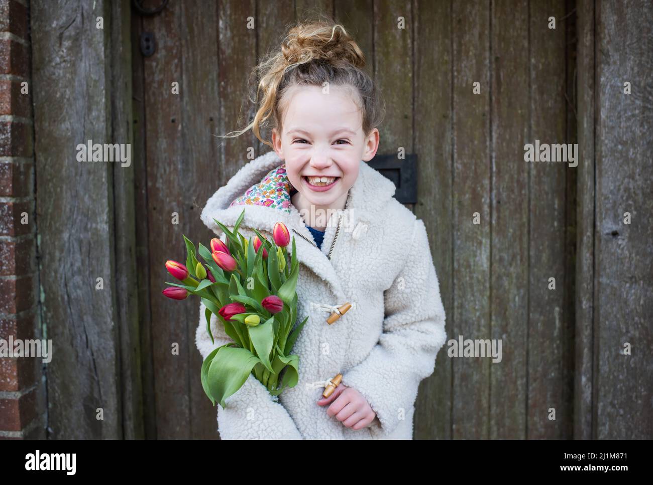 girl smiling holding flowers whilst walking outside Stock Photo