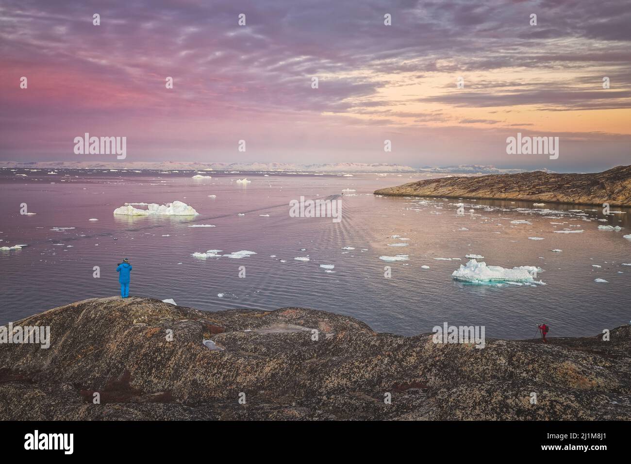 man observe the sunset in front of icebergs Stock Photo