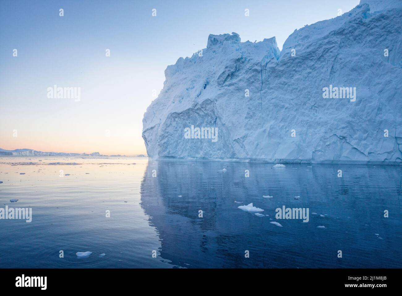Big icebergs floating over sea at sunset Stock Photo