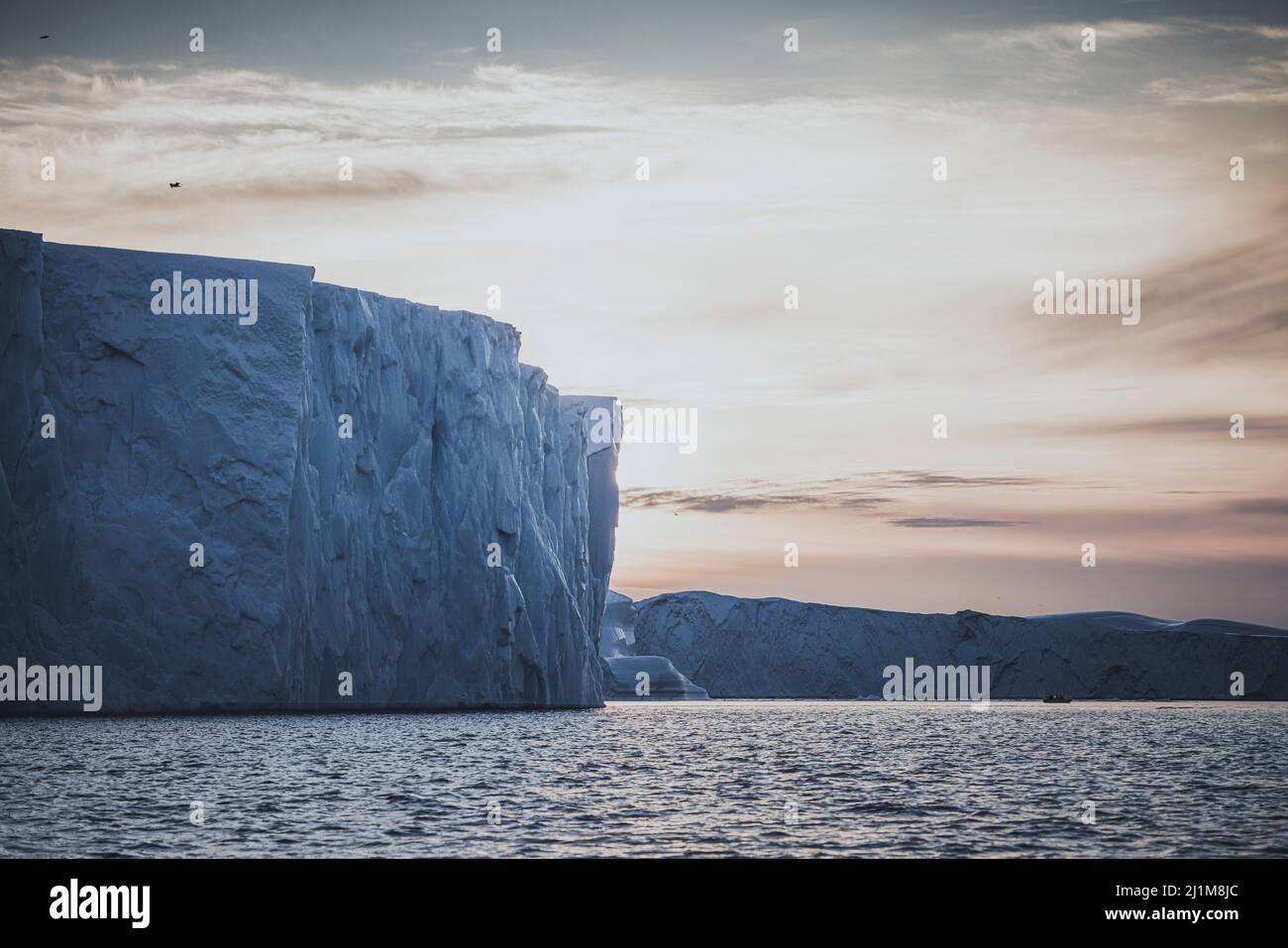 Big icebergs floating over sea at sunset Stock Photo