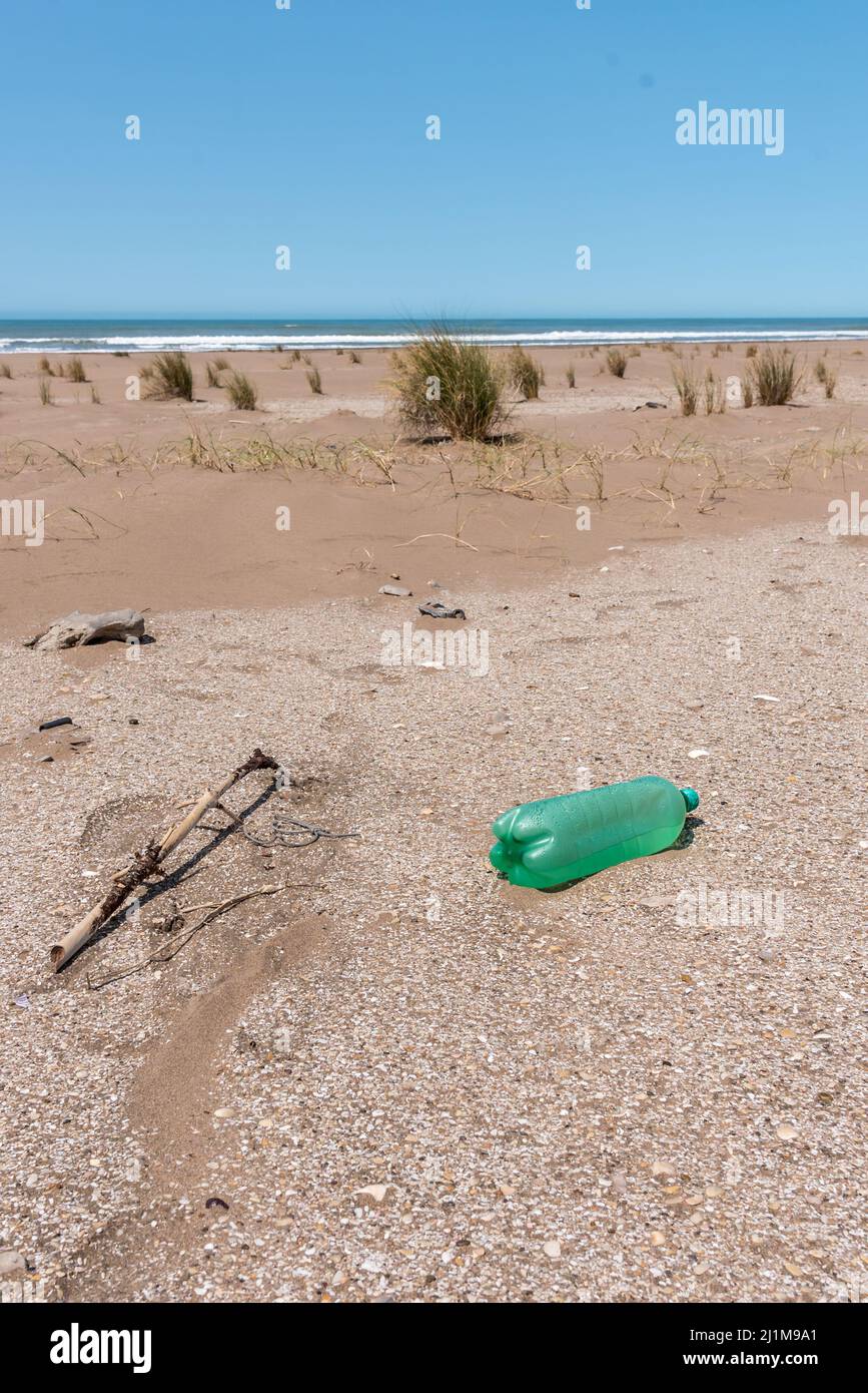 Plastic bottles lying on the sand near the beach and behind them you can see the horizon in the sea. Care of the earth Stock Photo