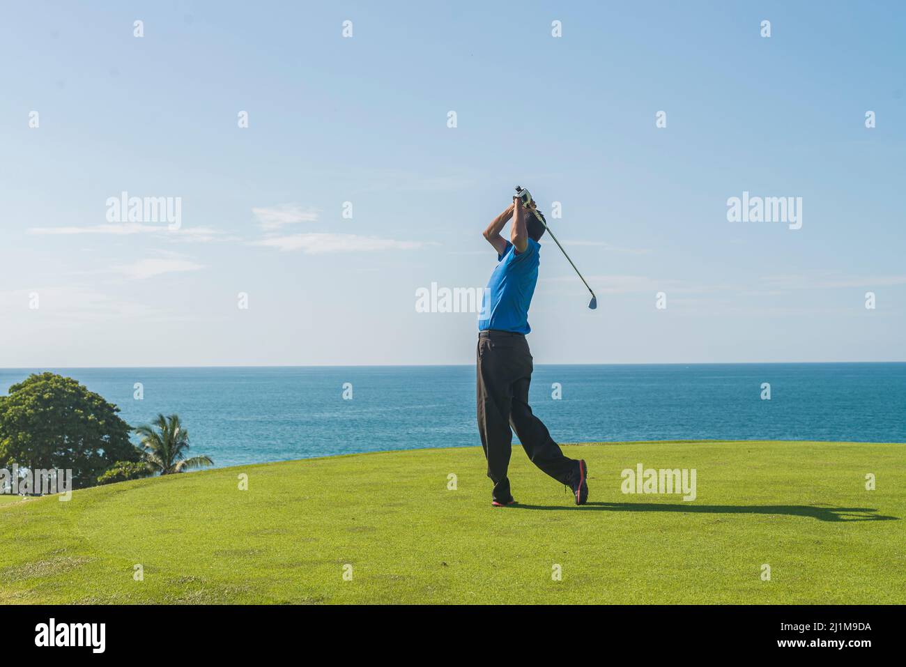 Latin golf instructor practicing his swing Stock Photo