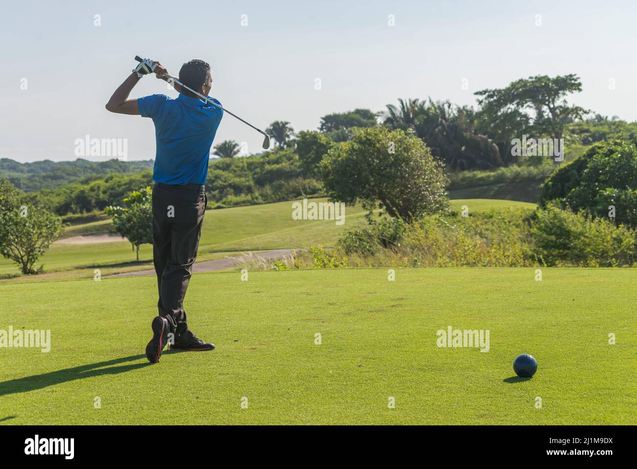 Latin golfer practicing his swing in the morning at the course Stock Photo