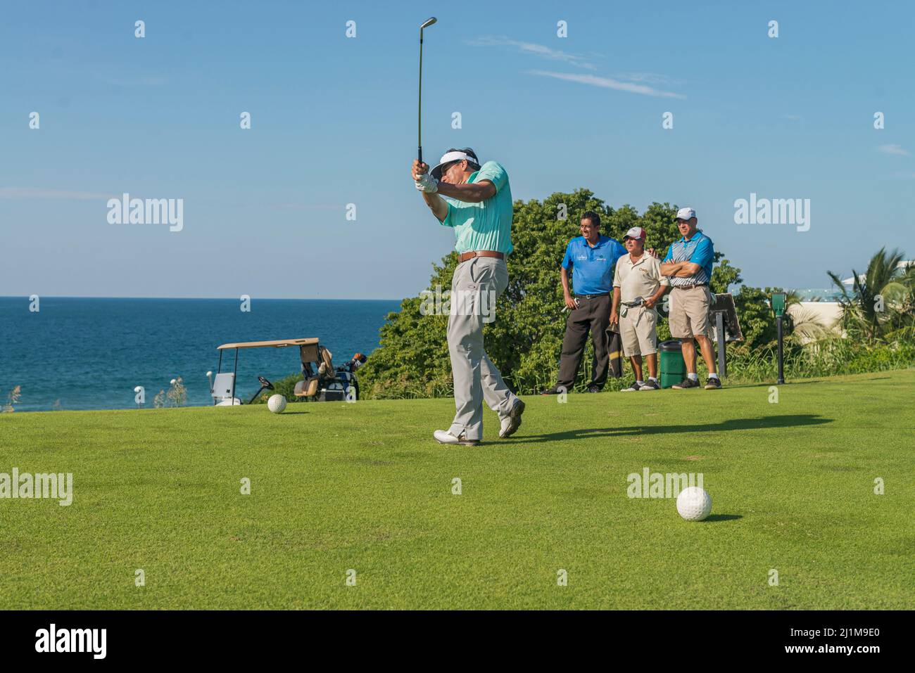 Group of latin golfers playing near the sea in the morning Stock Photo