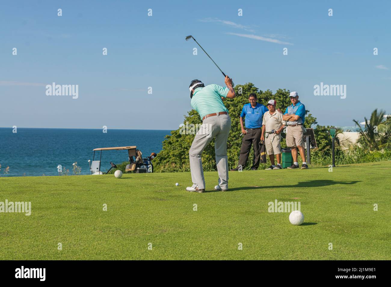Group of latin golfers playing on a course near the sea Stock Photo