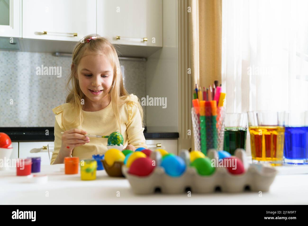 A smile girl paints easter eggs. Stock Photo