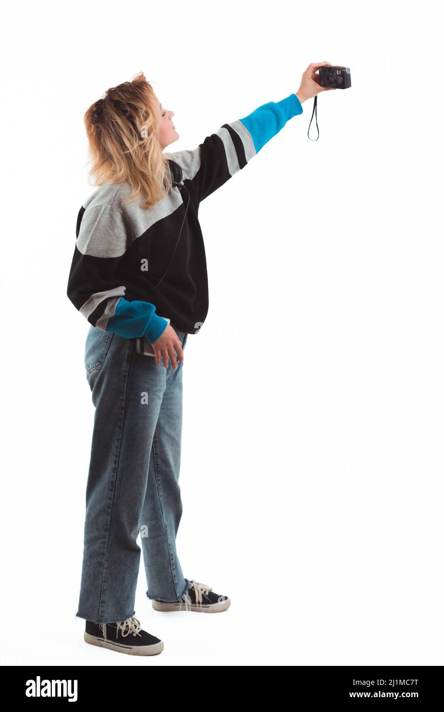 90s vibes. Girl taking selfie with vintage digital camera. Vertical studio shot. Copy space. White background. High quality photo Stock Photo