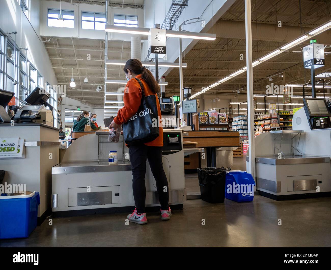 Lynnwood, WA USA - circa March 2022: View of a woman in a red coat checking out in the self-checkout area of a Town and Country Market Stock Photo