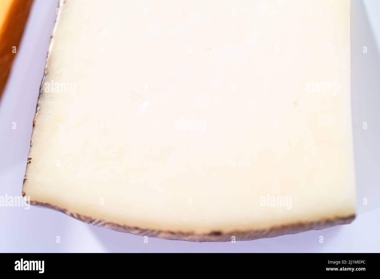 Large slice of aged Manchego cheese on a white background Stock Photo ...